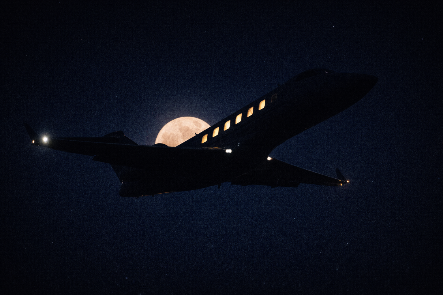 Private jet silhouetted against full moon at night